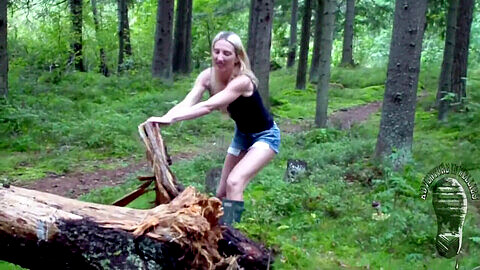 Bombe blonde joue avec des chasseurs verts dans la forêt, pieds nus et sans bottes