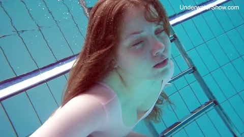 Simonna, the red-haired teen, flaunts her body underwater at a public pool