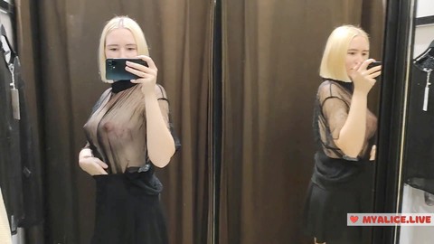 Die vollbusige Blondine probiert durchsichtige Kleidung in einer Umkleidekabine im Einkaufszentrum an