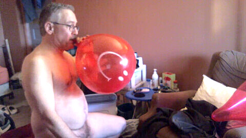 Retro-Gay-Szene: Reifer Mann lässt einen munteren Ballon platzen und befriedigt sich mit einem Toy