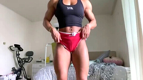 Japanische weibliche Bodybuilderin zeigt ihre Brustmuskeln, durchtrainierten Bauchmuskeln und stämmigen Bizeps in Pose.
