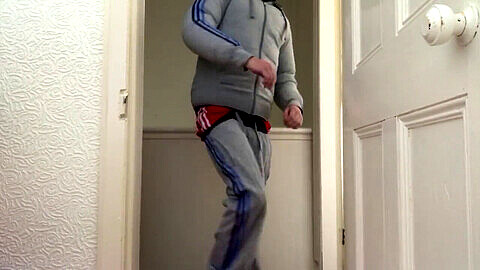 Britischer Teenager Chav in Puffa-Jacke und Adidas-Trainingsanzug befriedigt sich mit seinem Scally-Lad-Stil