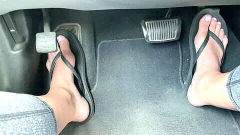 Hermosos dedos en parpadeantes sandalias pisando el acelerador del auto