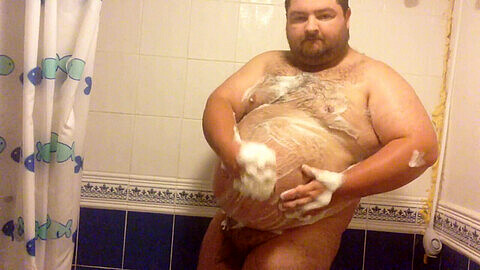 Un gars amateur et potelé prend une douche savonneuse dans la salle de bain tout en s'adonnant à ses désirs coquins